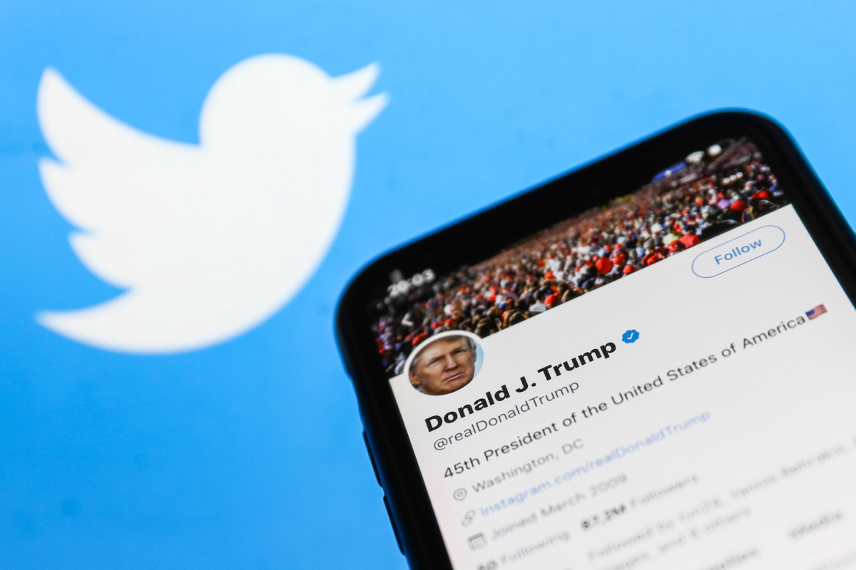 Twitter feed of the President of the USA Donald Trump is seen displayed on a phone screen with Twitter logo in the background